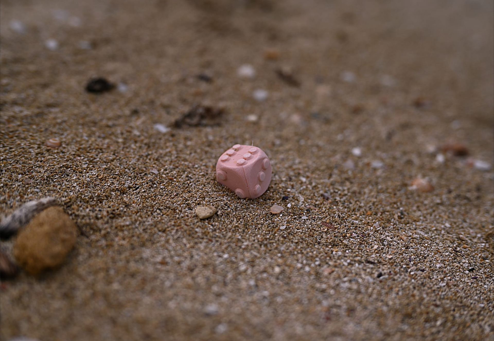 Rosa Würfel im Sand am Strand